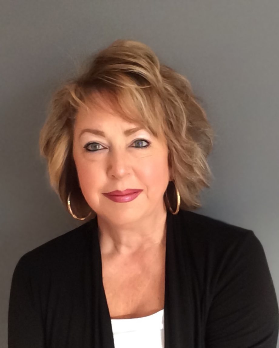 Professional headshot of an S&A Homes team member wearing a black cardigan and white top, smiling against a gray background.
