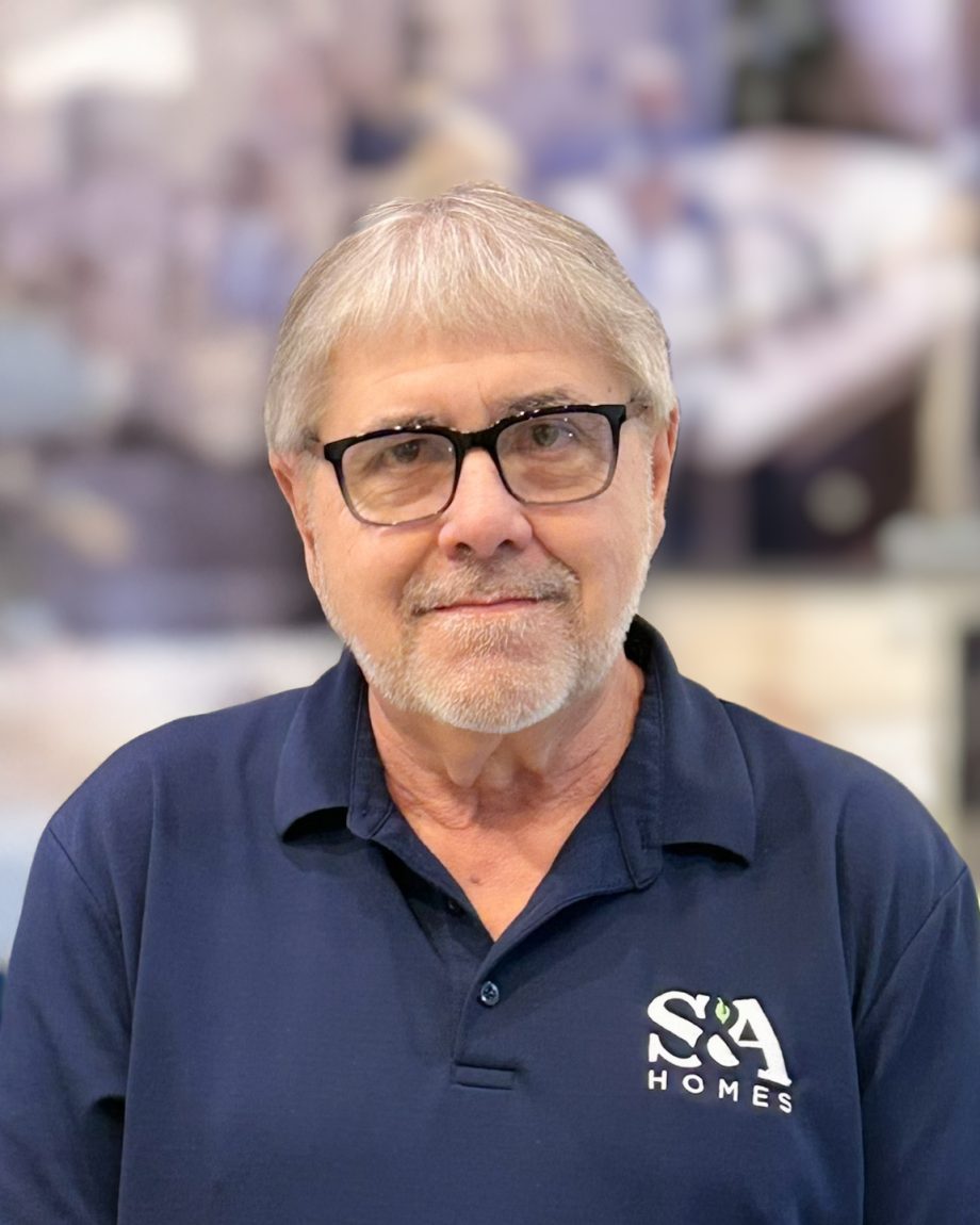 Professional headshot of an S&A Homes team member wearing glasses and an S&A Homes polo shirt, smiling indoors.