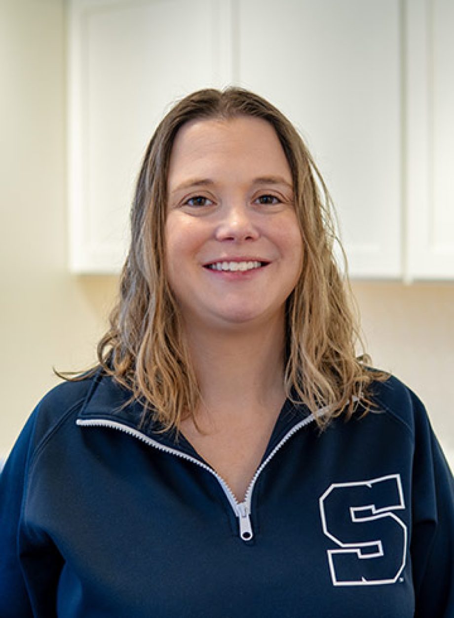 Professional headshot of an S&A Homes team member wearing an S&A Homes polo shirt, smiling in a model home kitchen.